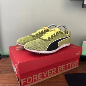 Spikskor - Säljer ett par spikskor från Puma med svart sidodetalj och vit sula. Skorna har snörning och är designade för optimal prestanda. Perfekta för löpning och träning. Inkluderar spikar för bättre grepp.