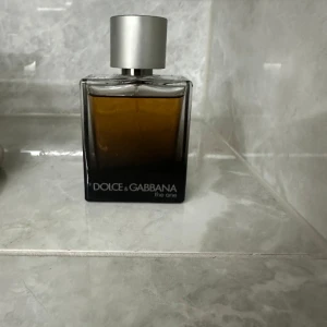 Parfym Dolce & Gabbana The One/som ni ser på bild är de ej rätt kork men rätt kork skickas med - Säljer en elegant parfym från Dolce & Gabbana, The One. Flaskan är fyrkantig med en stilren design och en silverfärgad kork. Doften är varm och inbjudande, perfekt för den som vill ha en sofistikerad touch. Rätt kork skickas med när ni köpt den.