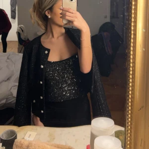 Svart glittrig jacka  - Säljer en svart glittrig jacka med knappar, använd 1 gång 