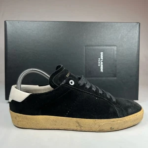 Svarta sneakers från Saint Laurent - Snygga svarta sneakers från Saint Laurent med en stilren design. Skorna har en vit häl och en beige sula som ger en cool kontrast. Perfekta för en avslappnad men trendig look.