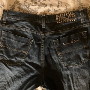 Mörkblå jeans med nitar - Snygga mörkblå vintage jeans som är köpta secondhand :) Har as kola nitar över ena bakfickan istället för en vanlig lapp, några saknas men tycker det ser lika bra ut ändå. Midjemått rakt över-  40 cm Ytterben- 100 cm Innerben- 75 cm Från grenen till midjan- 22 cm  Lårbredd 24 cm Benvidd nedtill -19 cm. De har en snygg light tvätt och är i bra skick. Är i relativt stretchigt material även om det är jeans. 
