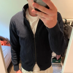 Mörkbkå fullzip - Dobber - Säljer en mörkblå stickad kofta från Dobber. Tröjan har hel dragkedja framtill, ribbade muddar och hög krage. Perfekt för lager-på-lager och enkel att matcha med olika outfits. Vid minsta fråga eller fundering hör av er🤝