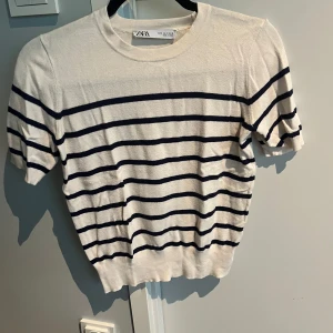 Vit och marinblå randig topp  - Säljer en fräsch vit topp från Zara med marinblå horisontella ränder. T-shirten har korta ärmar och rund halsringning. Perfekt för en stilren och avslappnad look. Skriv till mig för ytterligare frågor!😊🫶🩷