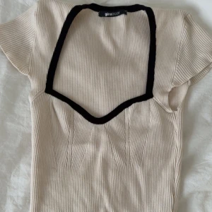Beige ribbad topp med svart kant från Gina Tricot - Använd 1 gång. 