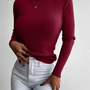 Ribbad vinröd polotröja - Säljer en vinröd ribbad polotröja med lång ärm. Tröjan är figurnära och har en klassisk polokrage. Perfekt att styla med jeans eller kjol för en snygg look. Sitter jättefint på kroppen. Ej använd bara provats en gång. 