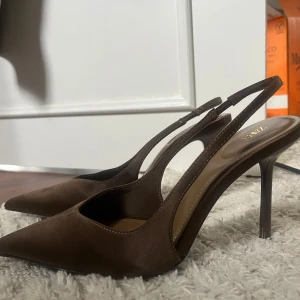 Klackskor - Säljer ett par snygga bruna klackar från Zara med smal klack och öppen häl. Skorna har en spetsig tå och är tillverkade i ett material som liknar mocka. Sälj då de tyvärr är förstora för mig, endast testade inomhus