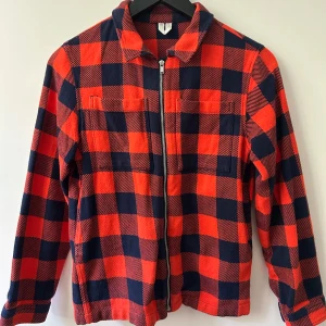 Arket Röd och marinblå rutig jacka med dragkedja 8-10 år - Säljer en röd och marinblå rutig jacka från arket i storlek 134/140, 8-10 år Jackan har dragkedja framtill, två bröstfickor, sido fickor och är långärmad. Perfekt för höst och vår, i mjuk bomullskvalitet.