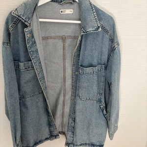 Oversized jeansjacka från Gina Tricot - Säljer en oversized ljusblå jeansjacka från Gina Tricot. Jackan har två stora bröstfickor, klassisk krage och knäppning framtill. Perfekt att slänga över en hoodie eller t-shirt för en avslappnad look. Pris kan alltid diskuteras. Xs/s. 