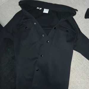 Svart skjorta från Selected Homme - Säljer en svart skjorta från Selected Homme med knappar framtill och två bröstfickor. Skjortan har lång ärm och klassisk krage, perfekt för en stilren look. 1000 kr ny 