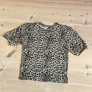 Leopardmönstrad topp med puffärm - Säljer en snygg leopardmönstrad topp med korta puffärmar. Toppen har rund halsringning och är i ett mjukt, stretchigt material. Perfekt för dig som vill sticka ut med ett djurmönster i garderoben.
