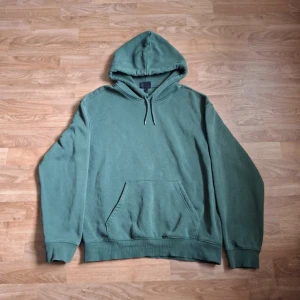 Grön hoodie från H&M - Säljer en grön hoodie från H&M i relaxed fit. Tröjan har huva med dragsko och en stor magficka framtill. Perfekt för en avslappnad stil och enkel att matcha med jeans eller joggers.