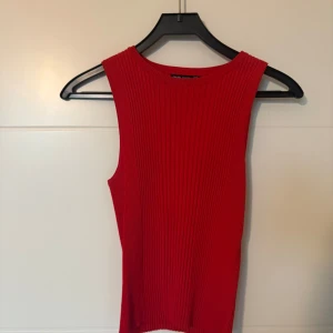 Röd ribbad linnetopp från Bershka - Säljer en snygg röd ribbad linnetopp från Bershka. Toppen är ärmlös och har en rund halsringning. Perfekt att styla till jeans eller kjol för en trendig look. Storlek M men passar även S då jag själv brukar bära S 