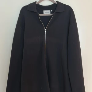 Svart tröja med dragkedja från Sandö - Svart långärmad tröja från Sandö med krage och dragkedja framtill. As snygg till sommaren. Storlek: M, men passar lika bra till storlek L. Skick: 9/10, knappt använd. Skriv till mig vid minsta fundering. Pris kan alltid diskuteras!