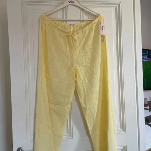 Gula linnebyxor från Nelly - Säljer ett par ljusgula linnebyxor från Nelly med resår och knytband i midjan. Byxorna har en avslappnad passform och är perfekta för varma dagar. Luftigt material som känns skönt mot huden.
