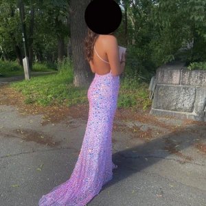 Lång glittrig klänning med öppen rygg - Glittrande festklänning – perfekt för bal, gala eller som gäst på fest!  Storlek: Small/medium  Pris: 1800 kr  En fantastisk långklänning i glittrande rosa/lila nyanser med öppen rygg och tunna axelband. Klänningen är täckt med stenar och paljetter som verkligen fångar ljuset och ger en wow-effekt. Storleken är mellan en small och medium då tyget är i stretch. Sitter  figurnära och har ett elegant släp som ger en extra lyxig känsla.  Använd en gång – i mycket fint skick!  💬 Vid snabb affär kan p