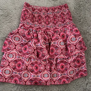 Gullig rosa kjol med mönster  - Kjol med inbyggda short, den är stretchug i midjan. jätte fint skick! Knappt använd. Två fläckar som är innuti som inte syns utanför kjolen. Går säkert bort i tvätten. Vet dock inte vart den är ifrån