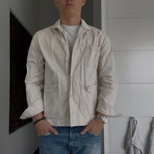 Beige overshirt från These Glory Days - Snygg beige overshirt från These Glory Days i bomull. Jackan har tre stora fickor framtill, klassisk krage och stängs med knappar. Perfekt att slänga över en t-shirt för en clean och avslappnad look.