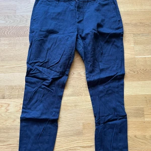 Mörkblå chinos - Snygga mörkblå chinos från Lager 157. Byxorna har sidofickor fram och två bakfickor med knappdetalj. Upplevs större i storleken, passar även M.