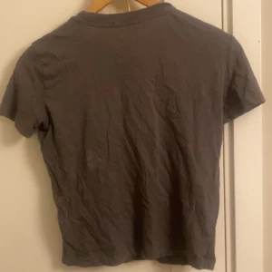 Mörkgrå basic t-shirt - En enkel mörkgrå t-shirt med korta ärmar och rund hals. Modellen är klassisk och passar perfekt till jeans eller shorts. T-shirten är i mjukt material och har en avslappnad passform. Den ser väldigt skrynklig ut men jag kommer tvätta den och stryka innan jag skickar iväg. 