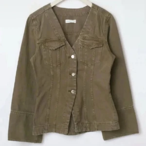 Jeans jacka Gina tricot - Snygg grön jeansjacka med v-ringad hals och markerade sömmar. Jackan har långa ärmar, två bröstfickor med lock och knäppning framtill med silvriga knappar. Perfekt för dig som gillar en stilren och avslappnad look.