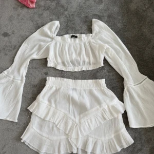 Vit croppad blus från Trendyol - Jättefint vit sett med en kroppad tröja med utsvängda armar och en kort kjol. Använd bara 1 gång. Perfekt sett för sommaren.