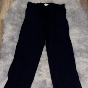 Marinblåa linnebyxor  från Gina Tricot - Marinblåa linnebyxor från Gina Tricot i storlek 158/164. De har en rak passform och är tillverkade i ett mjukt bomullsliknande material. Byxorna har resår i midjan och stora fickor framtill för en chill och enkel stil.