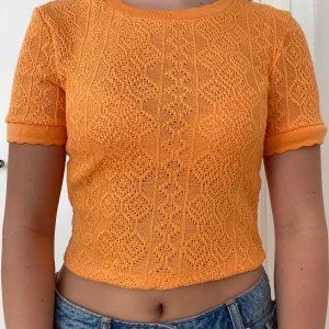 Orange Zara tröja - Supertrendig kort orange T-shirt från Zara. Jättefint stickat mönster med volangdetalj på krage och muddar. 