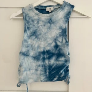 Blå tie-dye linnetopp med snörning - Snygg ärmlös linnetopp från River Island i blått och vitt tie-dye mönster. Toppen har snörning i sidorna som ger en cool rynkad effekt och kan justeras för perfekt passform. Perfekt för varma dagar och chill vibes.  
