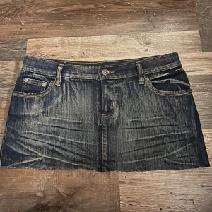 Mörk jeanskjol från Sarmoni - Mörkblå vintage jeanskjol från Sarmoni med slitna detaljer och klassiska fickor både fram och bak. Kjolen har låg midja,  synliga sömmar i kontrastfärg. Super fin nu till sommaren! Skulle säga den passar storlek 34/36🥰 vid snabb affär kan pris diskuteras!