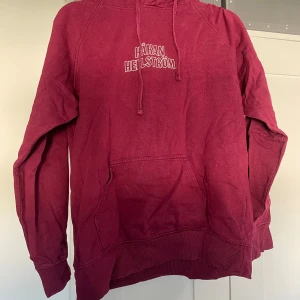 Vinröd Håkan Hellström hoodie - Vinröd hoodie med tryck av Håkan Hellström och texten 'Jag följer dig utför tillsammans i mörker'. Tröjan har huva med snörning, magficka och långa ärmar. Perfekt för dig som älskar svensk pop och vill ha en snygg och bekväm tröja. Liten i storleken och med uporispning i luvan.