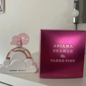 Ariana Grande Cloud Pink parfym - Superfin parfym från Ariana Grande, Cloud Pink. Flaskan är formad som ett moln med vit bas och rosa detaljer, och kommer i en glansig rosa kartong. Doften är söt och fräsch, perfekt för dig som gillar trendiga och lekfulla parfymer.
