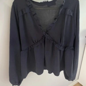 Mörkblå volangblus från Missay - Supersöt mörkblå blus från Missay med v-ringning och volangdetaljer framtill. Långa ärmar. Endast använd några gånger superfint skick 