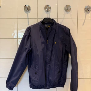 Vindjacka från Lyle & Scott - En vindjacka från Lyle & Scott i storlek 14/15 år. Jackan är i nyskick och har sällan kommit till användning. Nypris: 800 kr, Mitt pris: 200 kr. 