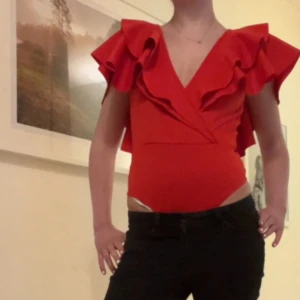 Röd body  - Säljer en röd body från Gina Tricot i storlek S☺️den är öppen i ryggen och har volanger! Super fin till fest eller nu till sommaren! 
