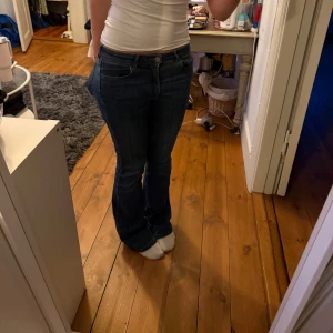 Mörkblå bootcut jeans - Säljer ett par mörkblå jeans med bootcut-modell och normal passform. Jeansen har klassisk design, knapp och dragkedja framtill, fickor fram och bak. Perfekta för dig som gillar en tidlös och enkel stil. Har slitits pyttelite nedtill men ansolut inget man tänker på när de är på!
