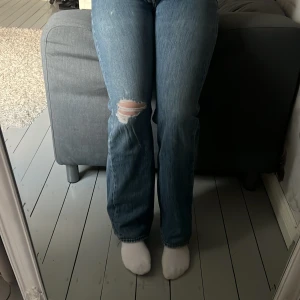 Levis bootcut - Säljer ett par klassiska blå bootcut jeans med en snygg slitning på ena knäet. Jeansen har normal passform och är tillverkade i denim.