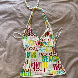 Vintage halterneck topp med tryck - Säljer denna vintage halterneck topp med texttryck i olika färger. Toppen har djup v-ringning, knyts i nacken och är öppen i ryggen. Går även att stylas som tubtopp. Perfekt för sommaren!💞