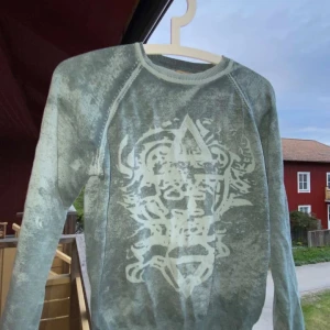 Grön sweatshirt från Jack & Jones - Skön blå sweatshirt från Jack & Jones med ett stort grafiskt tryck framtill. Tröjan har rund halsringning och långa ärmar. Perfekt för en avslappnad stil och passar bra till jeans eller joggers.