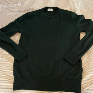 Mörkgrön tröja från Tiger of Sweden - Säljer en stilren mörkgrön tröja från Tiger of Sweden i storlek L. Tröjan har rund halsringning och långa ärmar, perfekt för en klassisk och enkel look. Passar bra till både jeans och chinos.