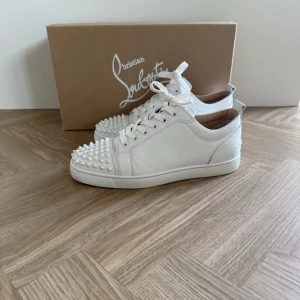 Christian Louboutin |As feta | ev byte - Säljer ett par vita sneakers från Christian Louboutin med ikoniska röda sulor och silverfärgade nitar framtill. | kan bytas mot förslag | skorna är äkta och använda 1 gång.