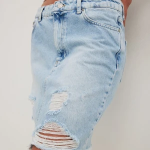 Blå jeanskjol från NA-KD - Trendig blå jeanskjol från NA-KD med slitna detaljer aldrig användt.