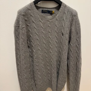 Stickad tröja i ull-kashmirblandning - Ralph lauren  - Klassisk stickad tröja i tidlös design, tillverkad i en mjuk och lyxig ull-kashmirblandning. Tröjan är i mycket fint skick – knappt använd och utan defekter. Perfekt till både vardags och mer uppklädda tillfällen. Ny pris 2 899 kronor. 
