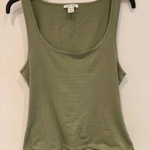 Olivgrön linnetopp från Amisu - Säljer en enkel och stilren olivgrön linnetopp från Amisu. Toppen har rund halsringning och är ärmlös, perfekt för varma dagar eller som lager under en skjorta. Mjuk och skön bomullskvalitet.