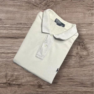 Ralph Lauren Piké – Vit (L) - Ralph Lauren Piké – Vit (L) 🤍  Säljer en klassisk vit pikétröja från Ralph Lauren i storlek L. En tidlös modell med perfekt passform och broderad logga – lika snygg till jeans som till chinos! Pikén har gulnat något med tiden, men det ger snarare en vintage-look än något dåligt – och priset är därför extra lågt! 	•	👕 Storlek: L 	•	📏 Mått: Längd 78 cm, armhåla till armhåla 60 cm, axel till axel 50 cm 	•	💸 Nypris ca 4000 kr 	•	⚠️ Billigt pris p.g.a. lätt gulnad + liten defekt (se sista bilden) 112