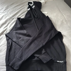 Svart hoodie från HUGO - Säljer en svart hoodie från HUGO med vit logga på huvan. Säljs inte i deras hemsida längre knappt använt som ny 