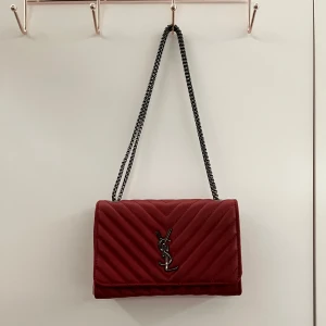 Brun quiltad handväska - Säljer en ”kakel”-brun quiltad handväska med kedjerem och logga i metall framtill. Väskan är köpt utomlands, den är inte äkta. Väskan har en elegant och stilren design, perfekt för att lyfta vilken outfit som helst. Kan användas som axelremsväska. Färgen är mycket ljusare i verkligheten. Har används 1-2ggr. Priset kan diskuteras. 