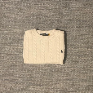 Vit stickad tröja från Polo Ralph Lauren - Säljer en stilren vit stickad tröja från Polo Ralph Lauren med kabelstickat mönster. Tröjan har långa ärmar och en rund halsringning. Perfekt för en klassisk och tidlös look. Sitter som en xs!