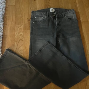 Grå jeansbyxor med raka ben - Säljer ett par grå jeansbyxor med klassisk femficksdesign och raka ben. Byxorna har knapp och dragkedja framtill samt bälteshällor i midjan. Perfekta för en avslappnad och stilren look.