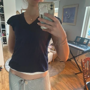 Mörkblå v-ringad topp med volangärmar - Säljer en mörkblå topp med v-ringning och korta volangärmar. Toppen har en enkel och stilren design som passar perfekt till både jeans och kjol. Materialet känns mjukt och bekvämt mot huden.