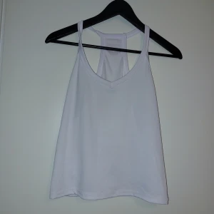 Vit ribbad linnetopp - Säljer en vit ribbad linnetopp med brottarrygg. Perfekt för sommaren och enkel att matcha med olika outfits. Tunt och mjukt material som känns skönt mot huden.Endast tvättad.